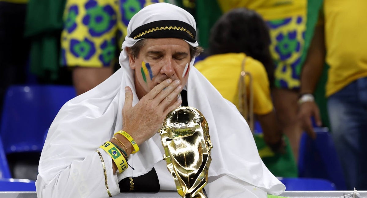 Un aficionado brasileño en Catar besa en la grada una réplica de la Copa del Mundo.