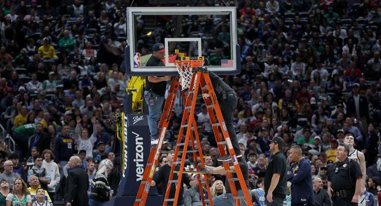 Los operarios de los Denver Nuggets intentan arreglar el aro destrozado en el Ball Arena de Denver.