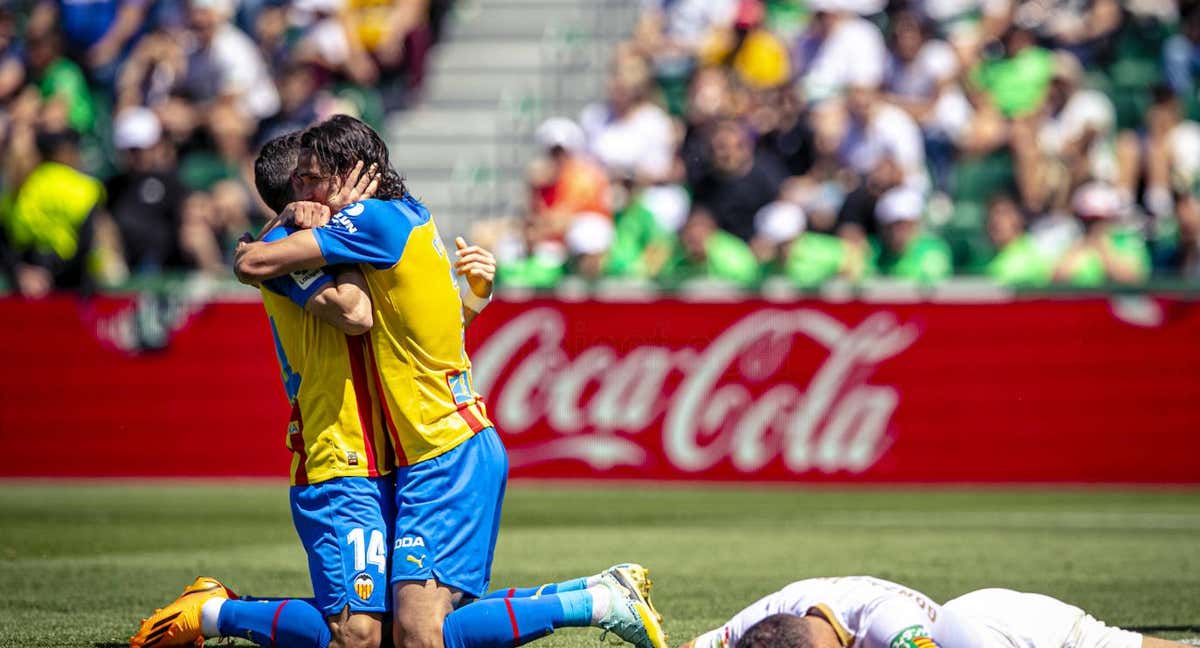 Gayà y Cavani se abrazan sobre el Martínez Valero. /Valencia CF.