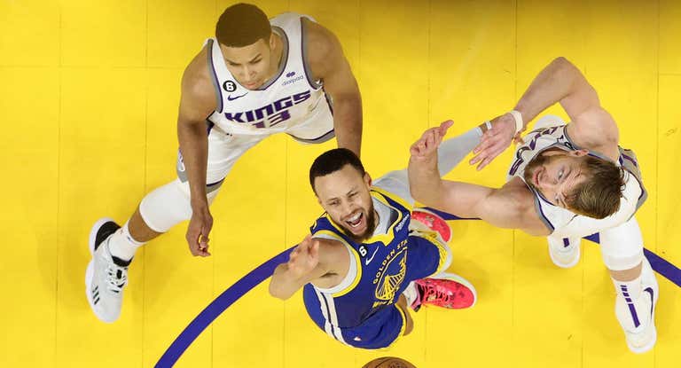 Curry intenta entrar a canasta con la oposición de Sabonis.