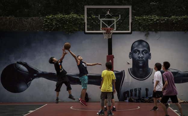 Frente a la imagen 'wings' de Jordan, unos chavales juegan al baloncesto en Beijing (China).  GETTY/ Kevin Frayer