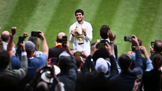 Carlos Alcaraz posa con la copa de campeón en la pista central de Wimbledon. /SEBASTIEN BOZON / AFP