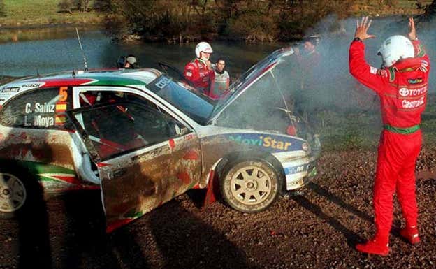 Luis Moya levanta las manos, con Carlos Sainz de fondo, tras la avería del Toyota Corolla en el Rally de Gran Bretaña 1998.  Reuters