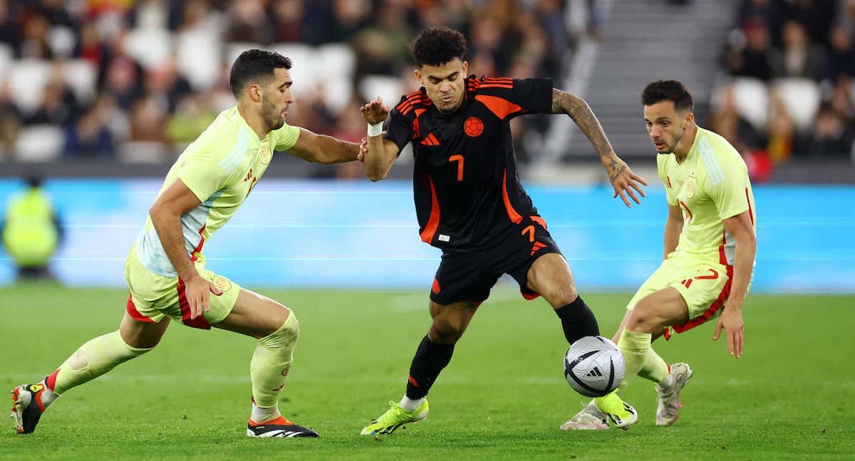 Mikel Merino pelea por un balón con Luis Díaz ante la mirada de Sarabia. /REUTERS