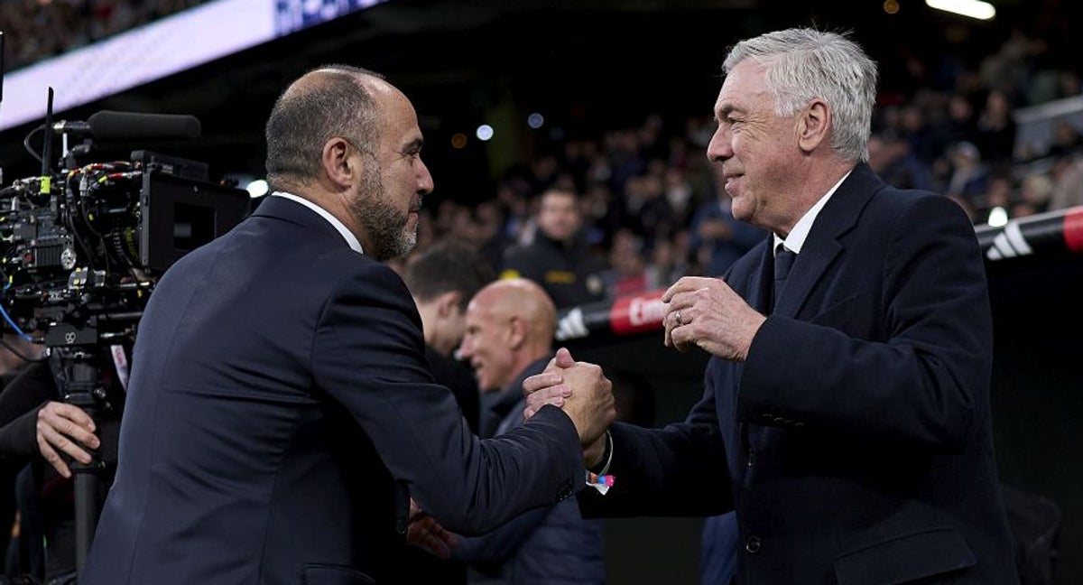 Chus Mateo se saluda con Carlo Ancelotti durante el homenaje al equipo de baloncesto en el Bernabéu tras ganar la Copa.