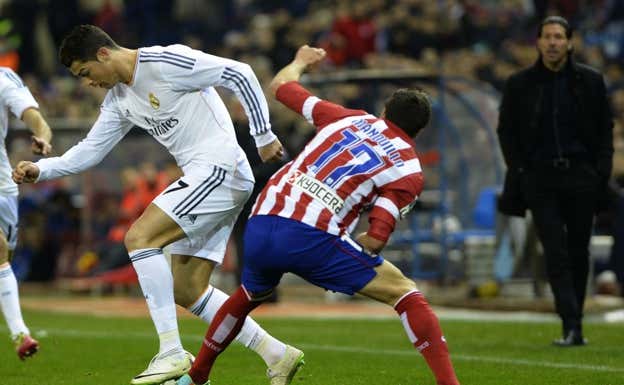 El canterano jugando un derbi con Simeone de fondo.  EFE