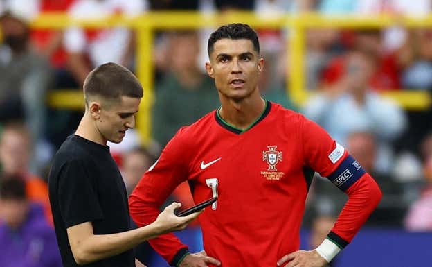 Cristiano, junto a un espontáneo en el partido de Portugal-Turquía.  REUTERS