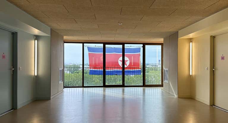 Imagen desde el interior del edificio de Corea del Norte en la Villa Olímpica, con la bandera del país colgada en el exterior.
