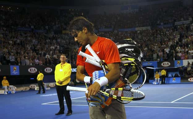 Rafael Nadal recoge sus raquetas durante el Open de Australia 2011.  REUTERS/Daniel Munoz